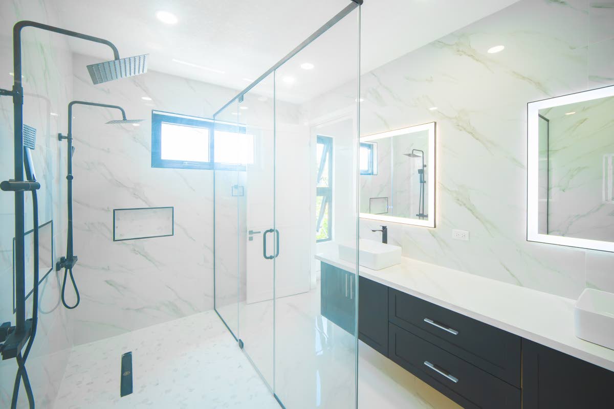 A floor-to-ceiling porcelain-walled bathroom, with a double sink floating vanity, and ‘his’ and ‘her’ glass-enclosed, walk-in rain shower.