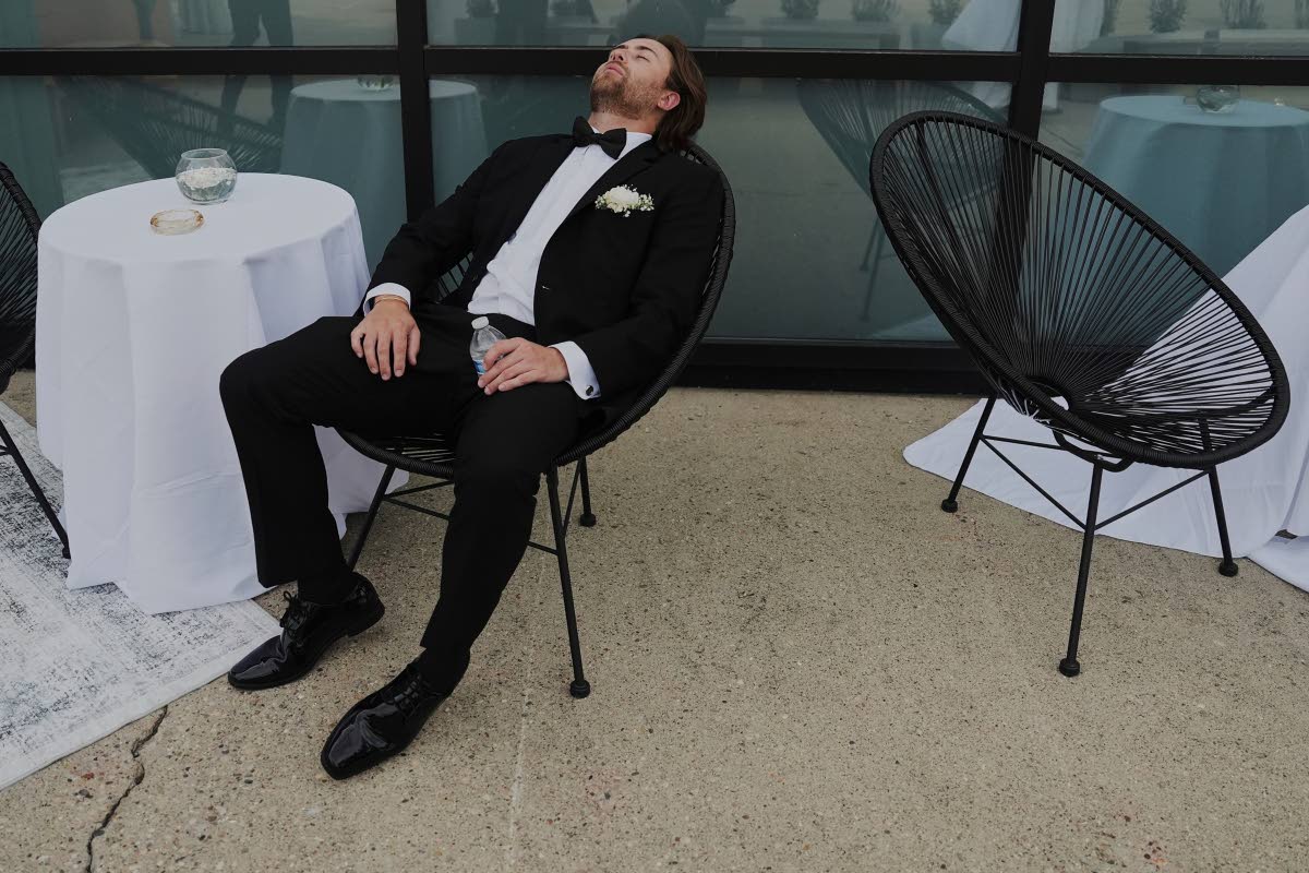 CENTRE RIGHT: A groomsman takes a break after finishing bridal party photos on Saturday, August 23, 2025, in Newtown, Ohio.