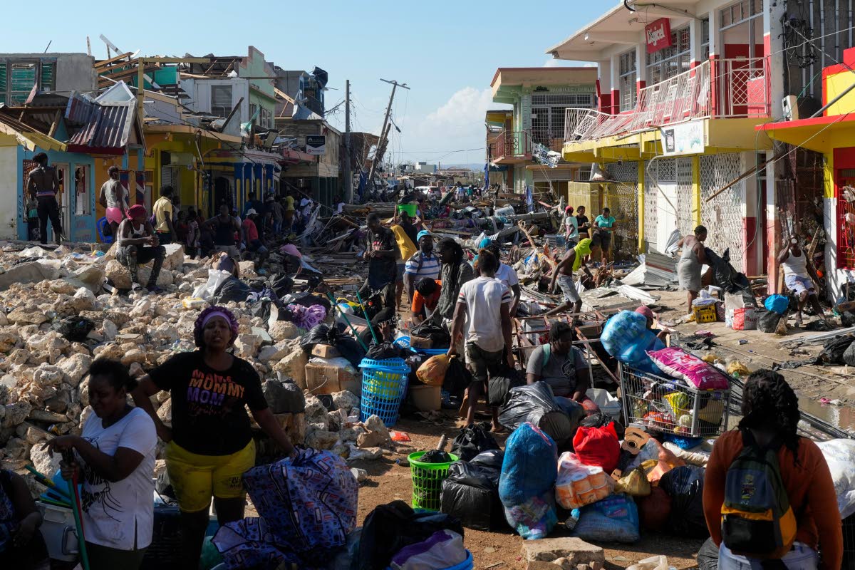 Residents gather amid debris in the aftermath of Hurricane Melissa on a street in Black River, Jamaica, on October 30, 2025. 