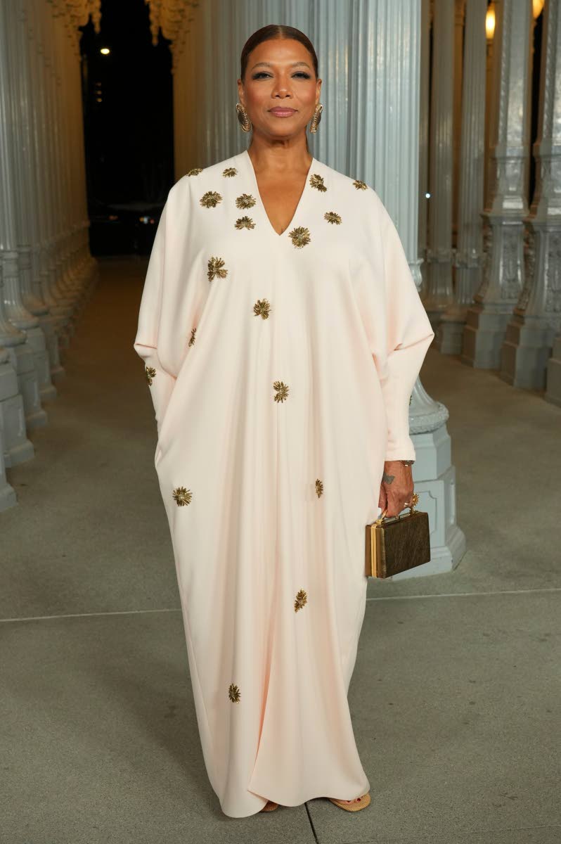 Kaftans are never out of style, and Queen Latifah rocks this earth-toned cream gown with gold appliques and a gold mini trunk.