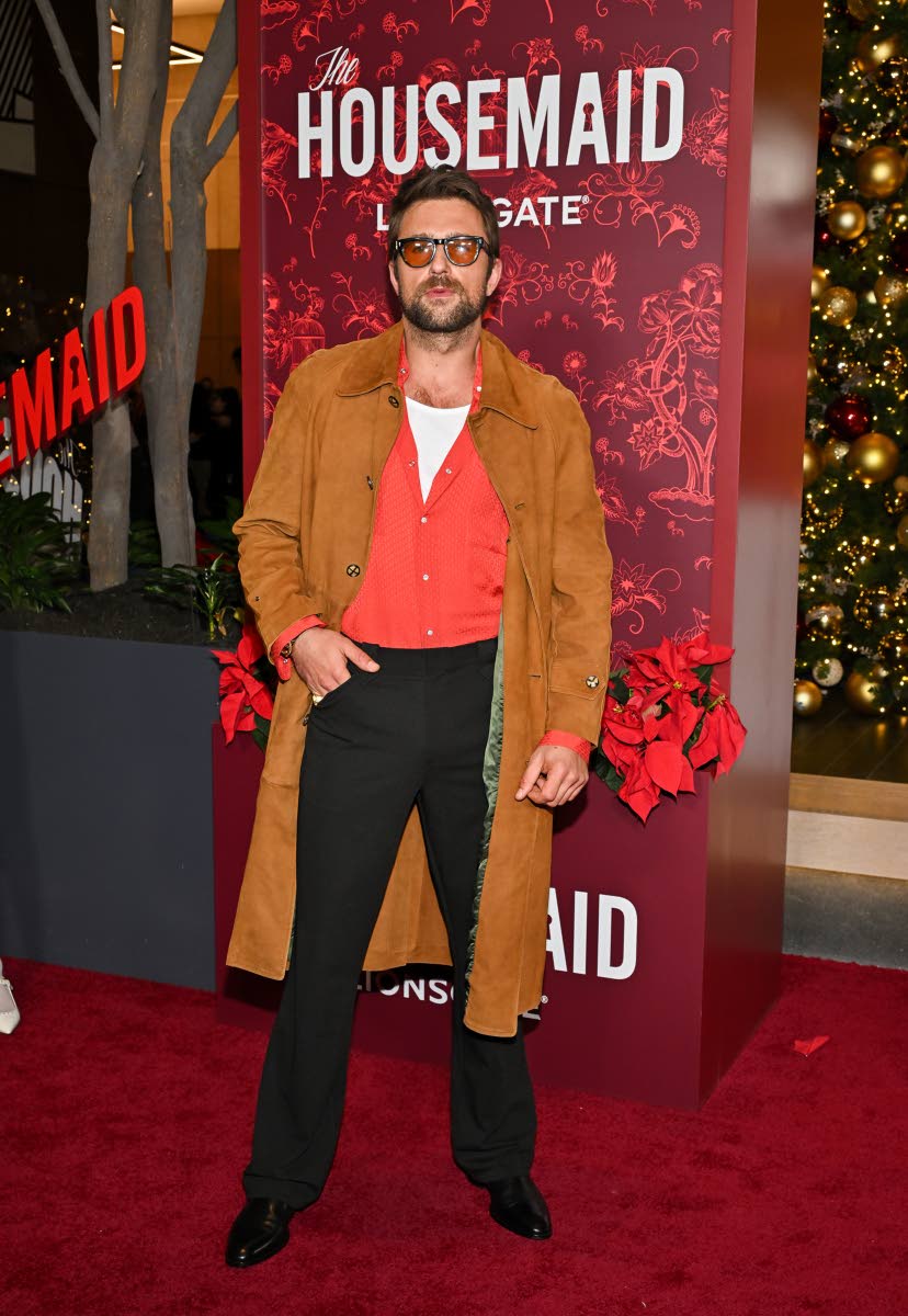 Brandon Sklenar opts for a relaxed take on evening style, pairing a camel trench with black trousers and a red shirt.