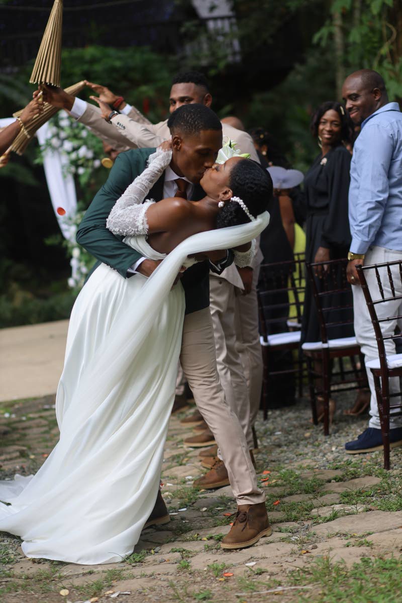 Just married! A joyful moment captured in the aisle as the wedding party celebrates the passionate kiss between the newly-weds.