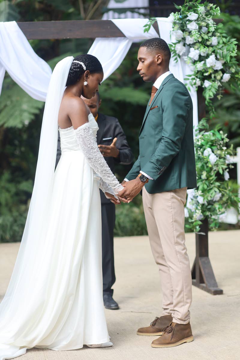The Laynes hold hands in prayer as officiant Andrae Dixon (back) blesses their union. 