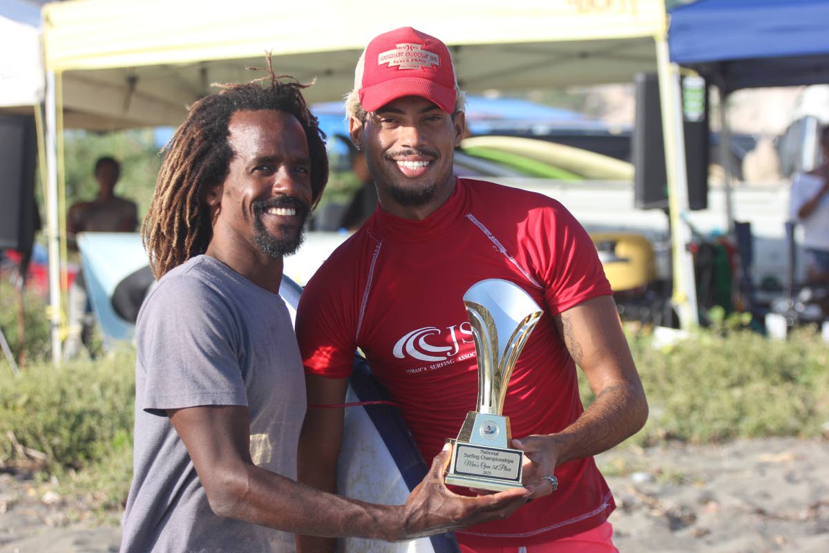 Jamaica Surfing Association competitions co-ordinator, Icah Wilmot (left), hands the National Surfing Championships winning trophy to Elishama Beckford at the Copa Beach on Sunday.
