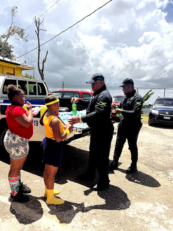 Sergeant Kenneth McTavish and Constable Hermitt serve bottled beverages to students during the Easter treat.