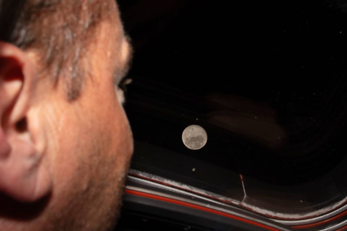 In this photo provided by NASA, Artemis II commander and NASA astronaut Reid Wiseman looks out one of the Orion spacecraft's main cabin windows at the Moon ahead of the crew's lunar flyby on April 6, 2026. (NASA via AP)