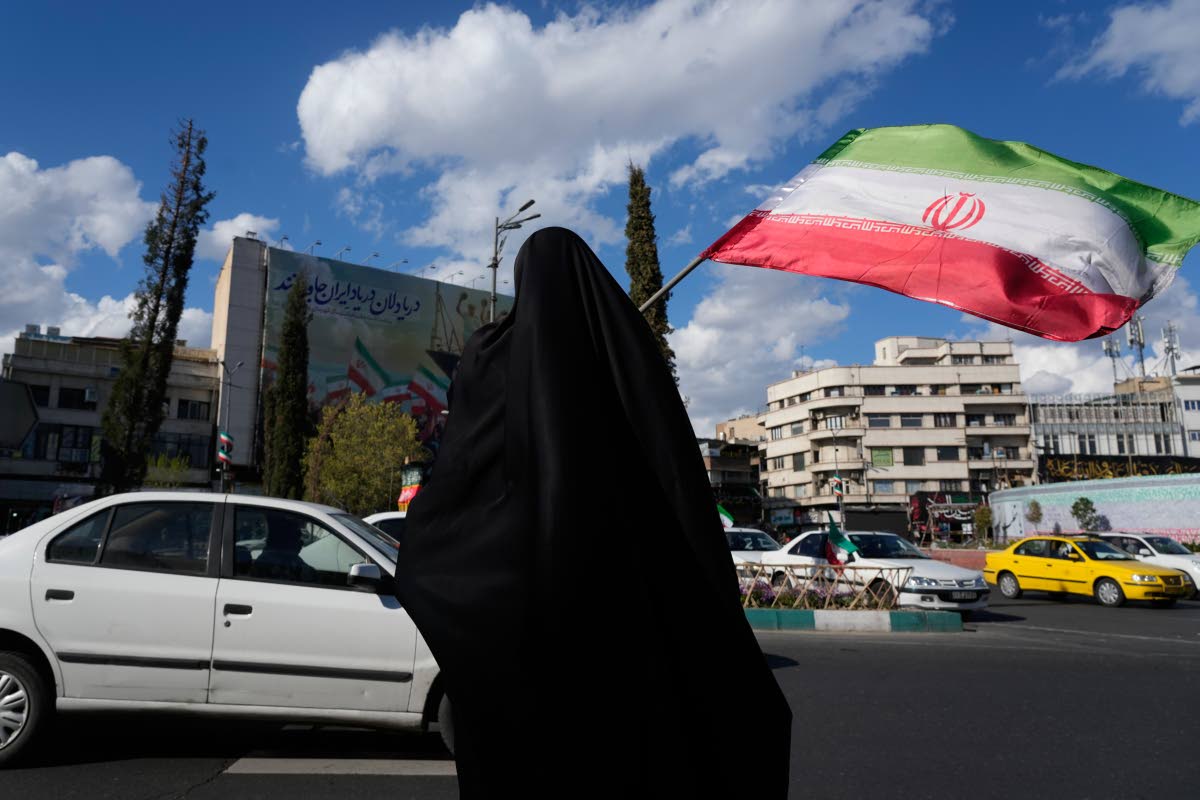 A woman waves an Iranian flag during a campaign in support of the government at the Enqelab-e-Eslami, or Islamic Revolution, square in downtown Tehran, Iran, Monday, March 30, 2026. (AP Photo)
