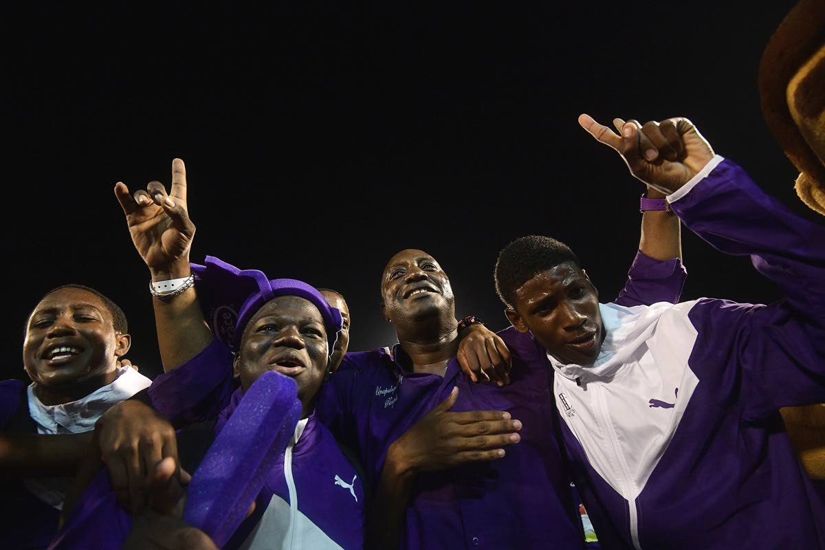 Kingston College principal Dave Myrie (centre) celebrates with athletes after winning the 2019 Boys’ title at Champs.