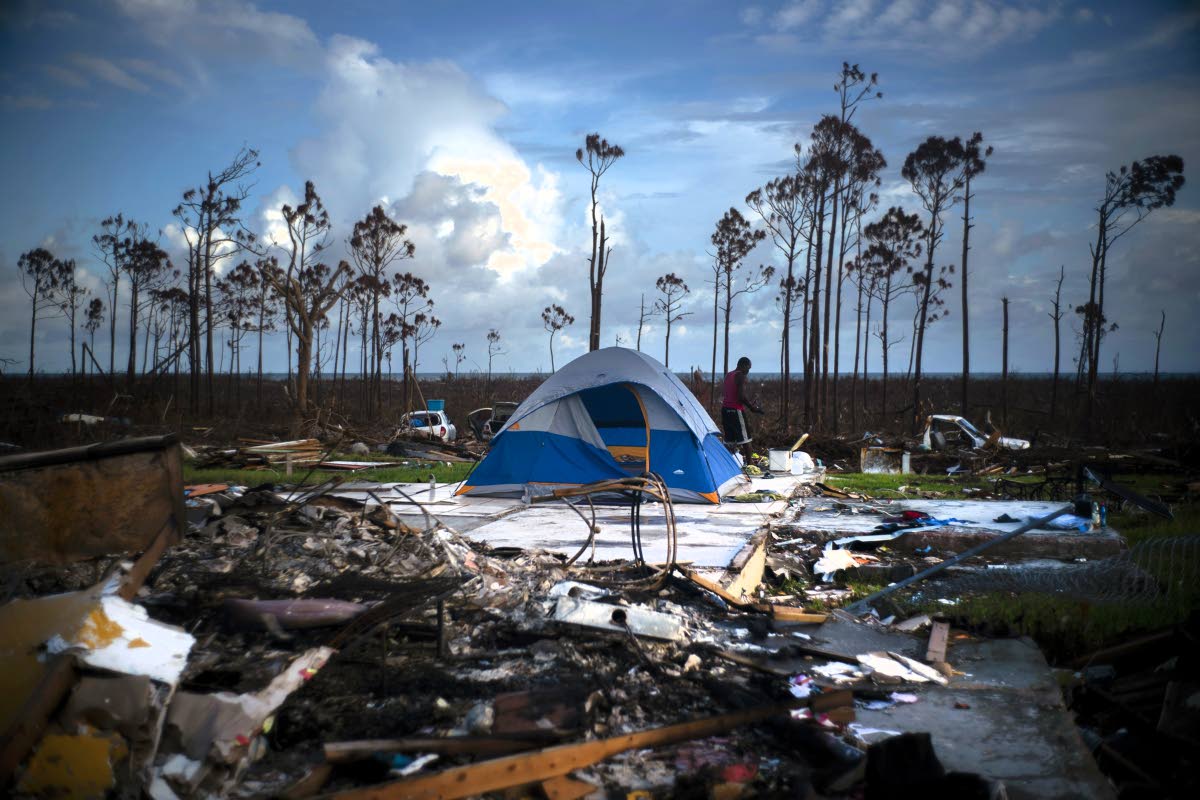 This 2019 photo shows a man searching in the rubble of his house destroyed by Hurricane Dorian in Rocky Creek East, Grand Bahama, Bahamas.