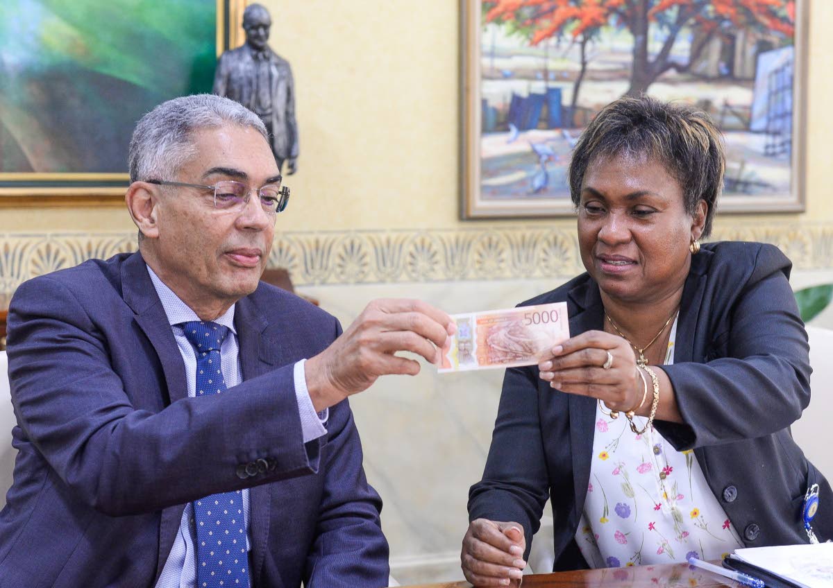 
Bank of Jamaica (BOJ) Governor Richard Byles (left) examines features on the new $5,000 note, being highlighted by BOJ Division Chief for Banking and Currency Operations, Chevanese Morais.