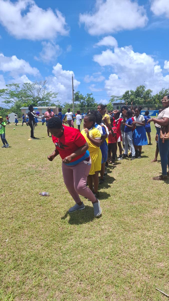 Principal Marva Davis-Clarke leads the students, teachers, and parents in an energetic ‘Follow the Leader’ dance around the school compound.