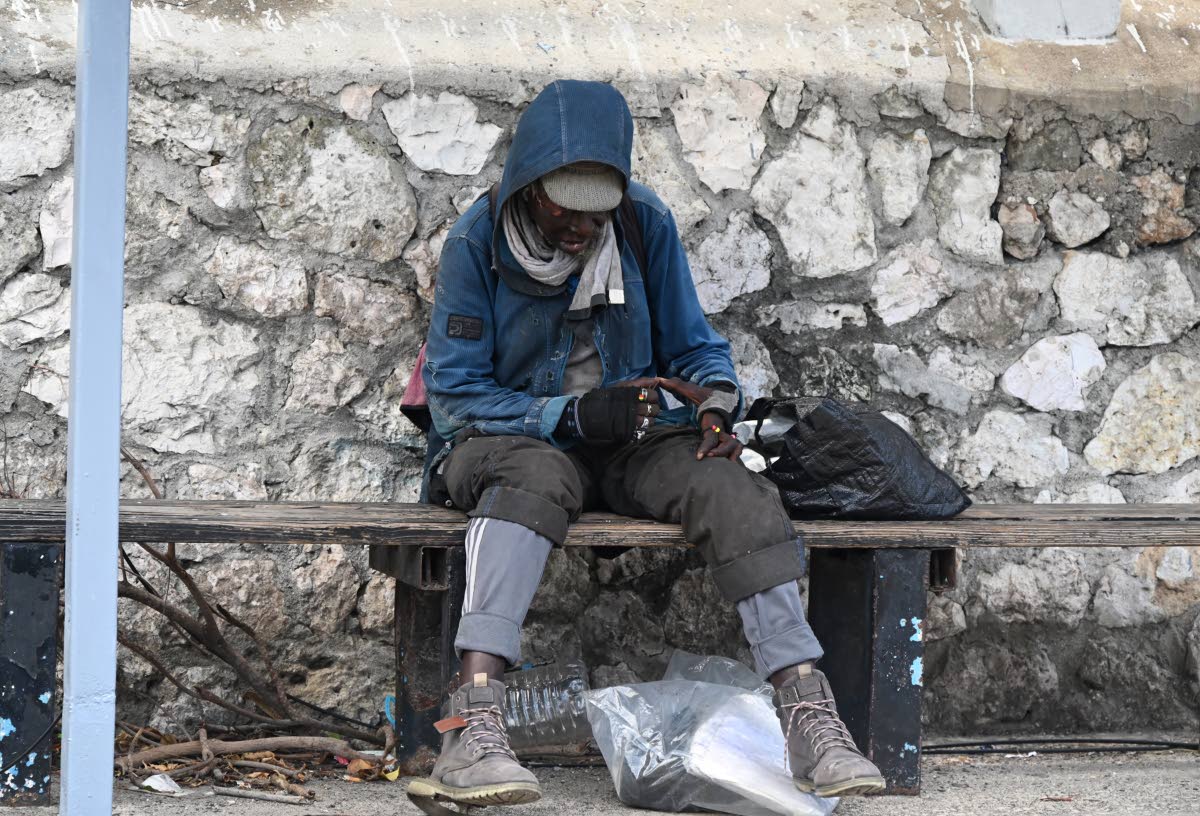 A homeless man occupies a space beneath a bus stop along Jimmy Cliff Boulevard in Montego Bay, St James, on Friday.