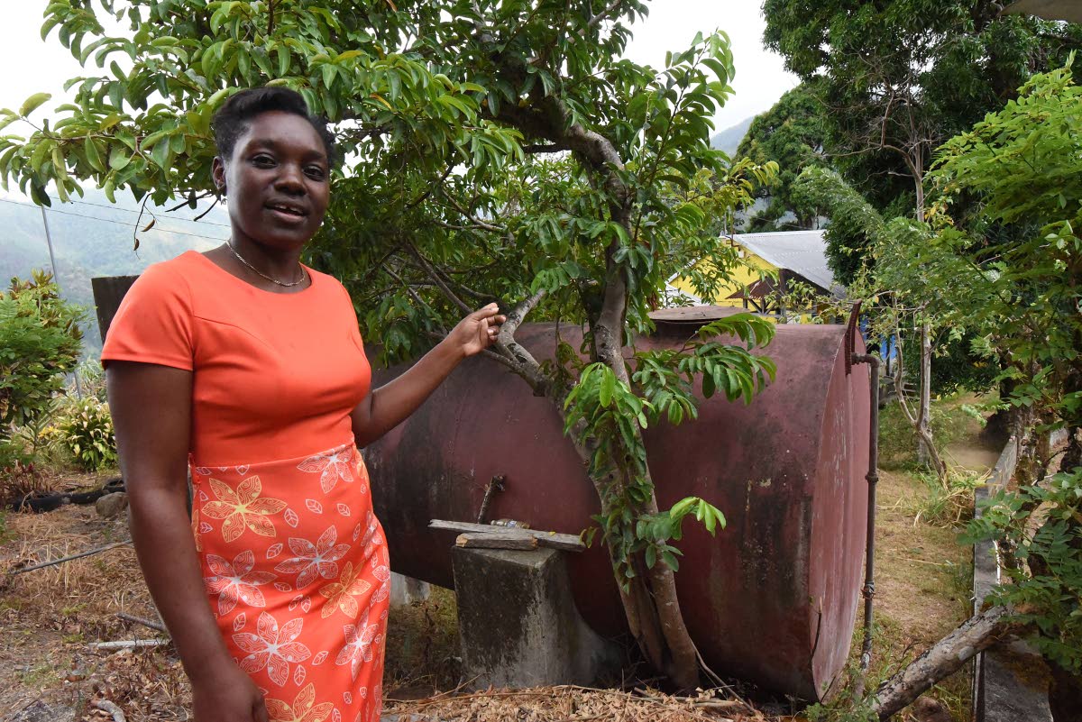 Julane King-Walker, principal of Claverty Cottage Primary School, shows off a 3,000 gallon water tank that has helped the school survived the long drought that has been affecting the island.