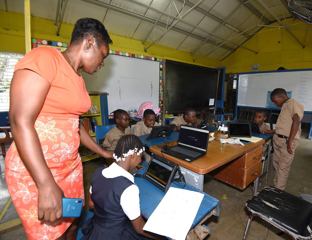 Julane King-Walker, principal of Claverty Cottage Primary School, helps the six students in attendance as they use their tablets.