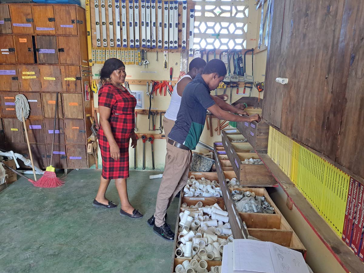 Patricia Gillings-Smith (left), head of the Industrial Arts Department at Muschett High in Trelawny, oversees students working on plumbing-related projects at the school last week. A section of the plumbing laboratory is still under renovation after being 