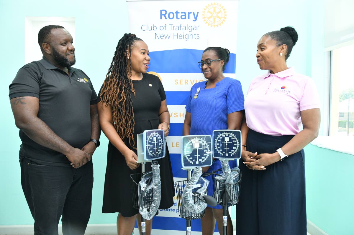 Franchesca Francis (second left), immediate past president of the Rotary Club of Trafalgar New Heights, makes a point to Suzette Buchanan (right), CEO of the Bellevue Hospital, as she presents three Medline mobile aneroid blood pressure monitors being dona