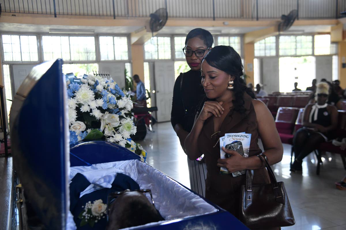 Kimone Francis (left), vice president of the Press Association of Jamaica, and Taneisha Mundle, senior journalist at the RJRGLEANER Communications Group, view the body of late veteran journalist Balford Henry before the start of his funeral ceremony at the