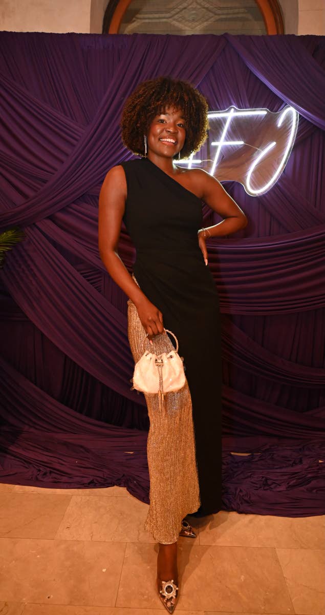 Model Dani Scott flaunts her fro in a one-shoulder maxi dress, featuring a daring side slit with a gold inset, paired with a matching clutch.