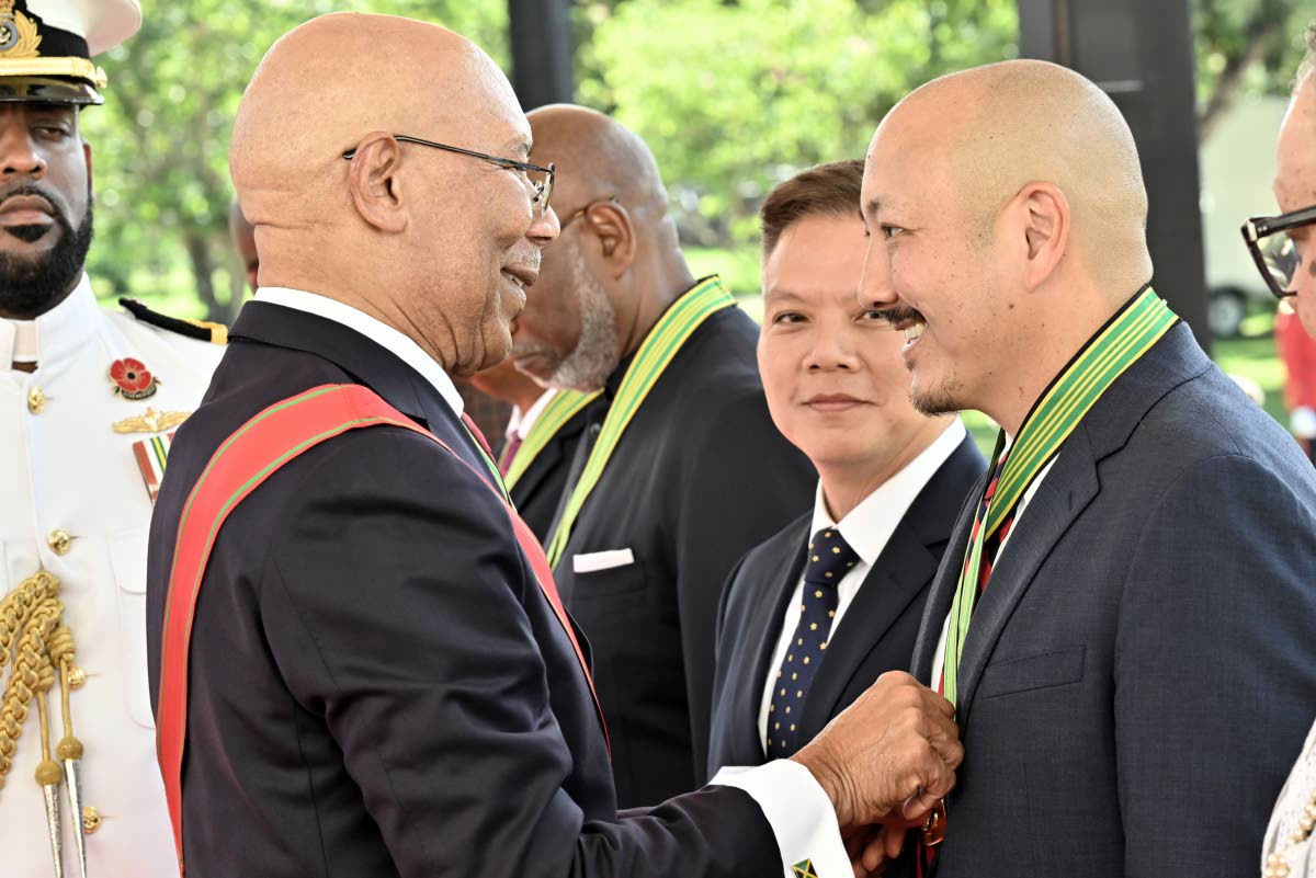 Governor-General Sir Patrick Allen pins the Order of Distinction in the Rank of Commander on Matthew Lyn during the National Honours and Awards Ceremony. Also pictured is Bruce Loshusan (centre), who accepted the award on behalf of the late Kenneth Loshusa