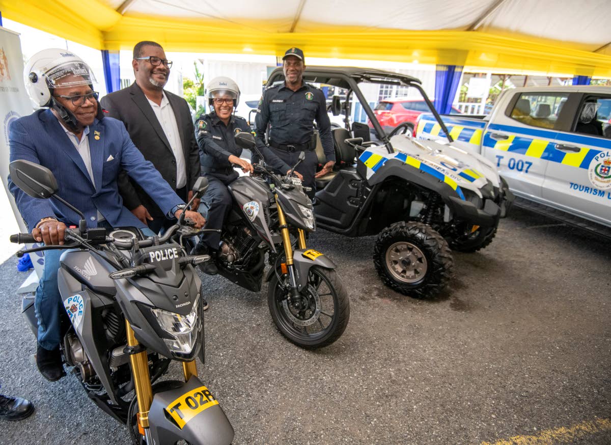 From left: Tourism Minister Edmund Bartlett sits on one of the motorcycles being handed over to the police by the Tourism Product Development Company at the Elleston Road Police Station in Kingston on Tuesday. Sharing in the occasion are Wade Mars, executi