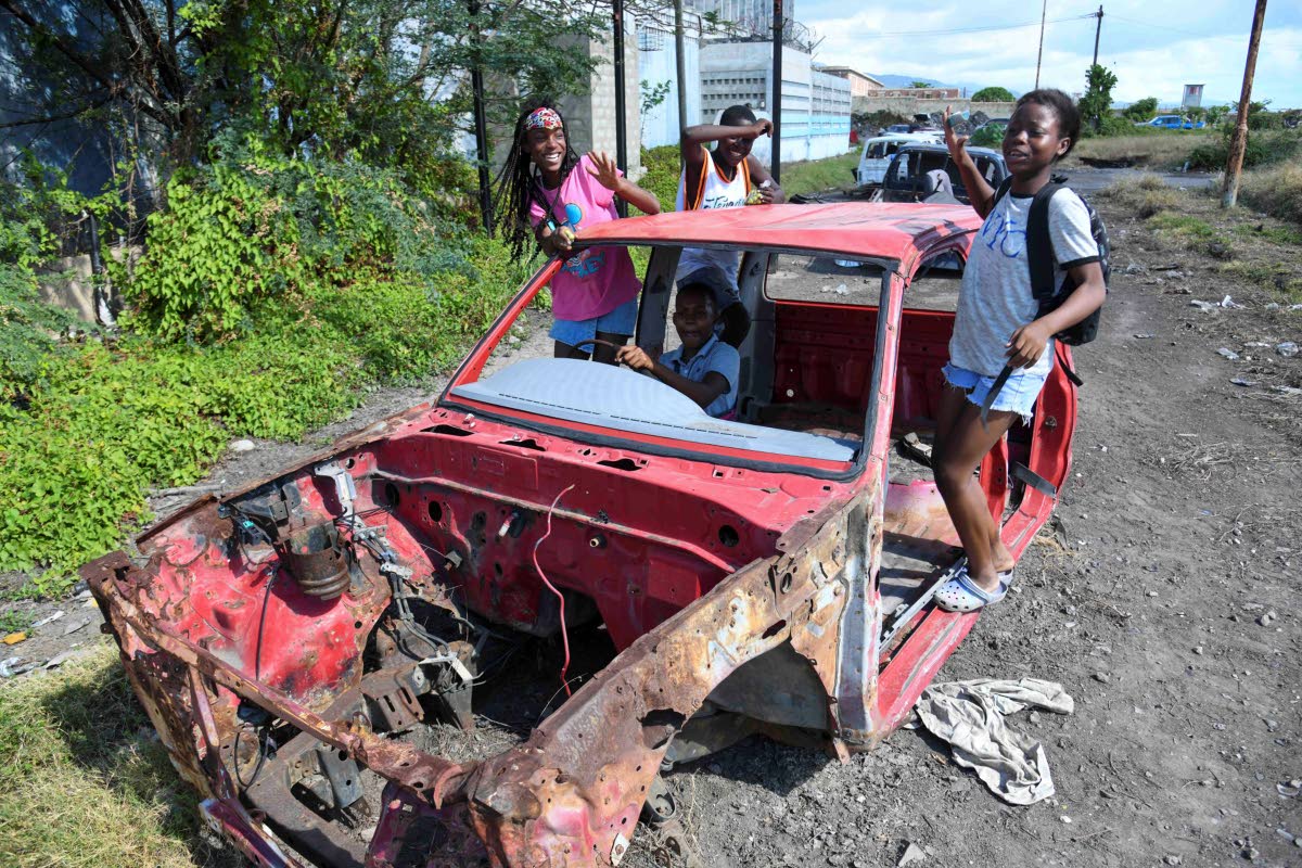 Children play in an abandoned car at the intersection of South Camp Road and Harbour Street in downtown Kingston on January 2 this year.