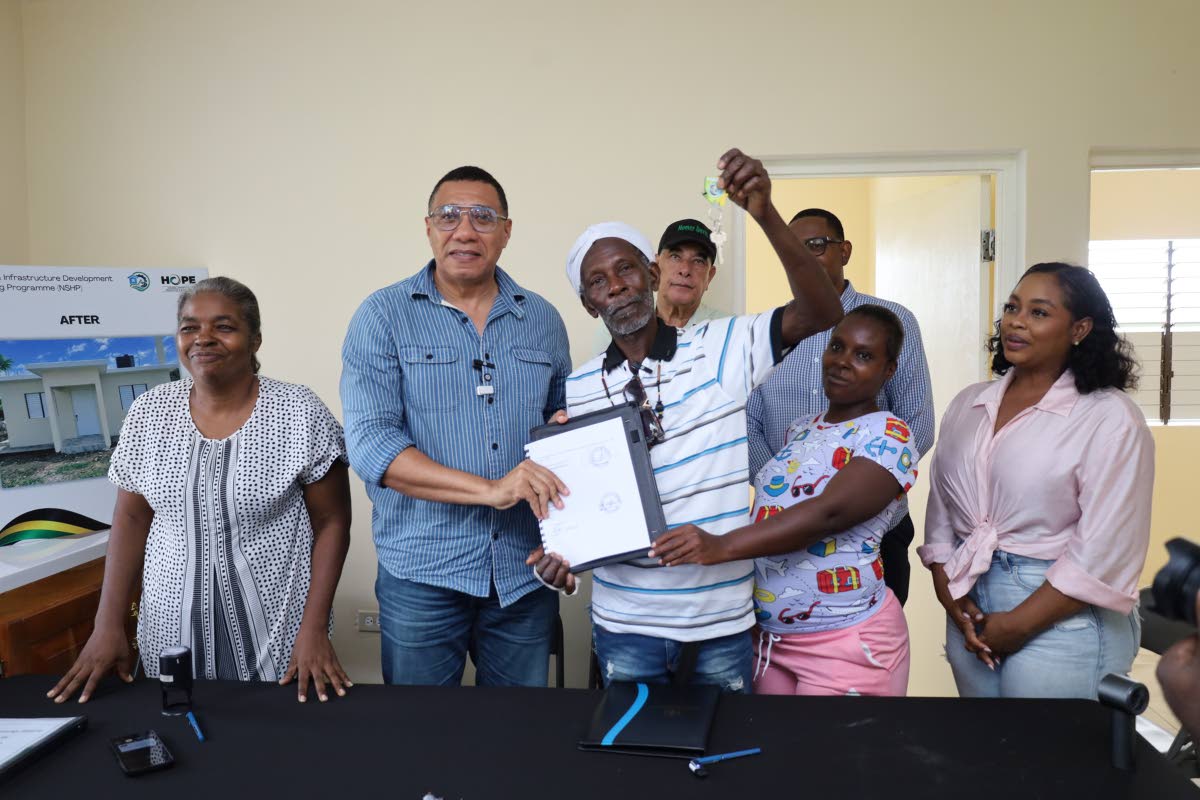 Barrington Dobson (centre), a beneficiary of the Government’s New Social Housing Programme (NSHP), accepts the contract and keys to his new three-bedroom house from Prime Minister Dr Andrew Holness (second from left) during a handover ceremony last Frida