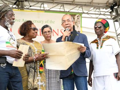 Deputy Prime Minister and Minister of National Security, Dr Horace Chang (second right), and Minister of Culture, Gender, Entertainment and Sport, Olivia Grange (second left), examine certificates of title for lands transferred to the Rastafari Coral Gard