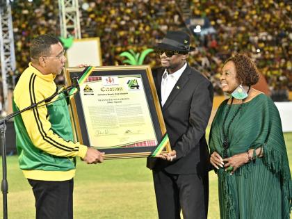 Dancehall artiste Busy Signal (centre) accepts the Reggae Icon Award from Prime Minister Holness as Minister Grange looks on. 