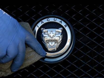 A worker polishes a Jaguar logo on a car at a Jaguar dealer in London, Wednesday, September 28, 2016. 