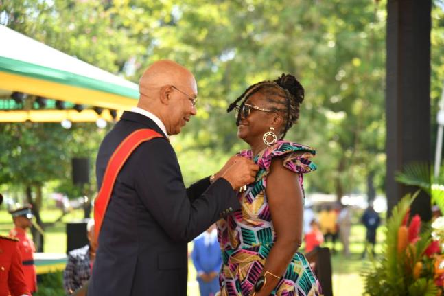 Dr Michelle Holt (right) is all smiles as she receives the Order of Distinction from Governor General Sir Patrick Allen during the Ceremony of Investiture and Presentation of National Honours and Awards on the lawns of King’s House yesterday.