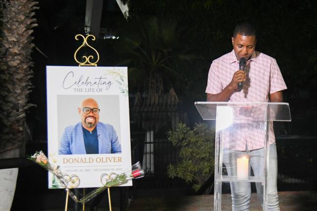 Sports journalist Ricardo Chambers reads an excerpt from Donald Oliver’s unpublished book at the Donald Oliver Candlelight Vigil held at Statue Park, National Stadium on Thursday night.