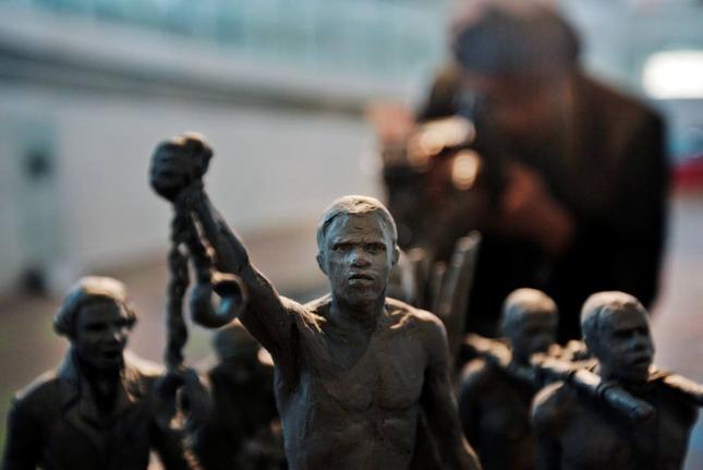 A man photographs a maquette of a statue, at City Hall, London.