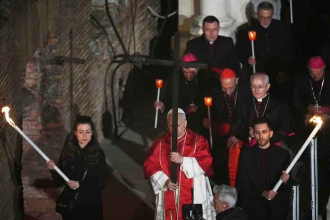 Pope Leo XIV carries a lightweight, 1.5-meter (5-foot) wooden cross during the Via Crucis, the torchlit Good Friday Stations of the Cross procession at the Colosseum in Rome, Friday, April 3, 2026, which symbolically retraces Jesus Christ's steps to his cr